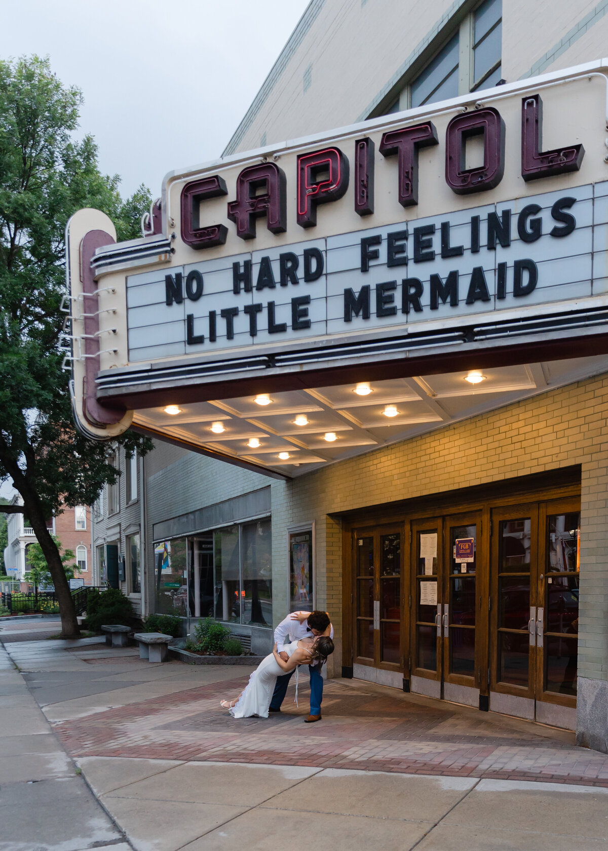 Bride and groom kiss under marquis lights in downtown montpelier
