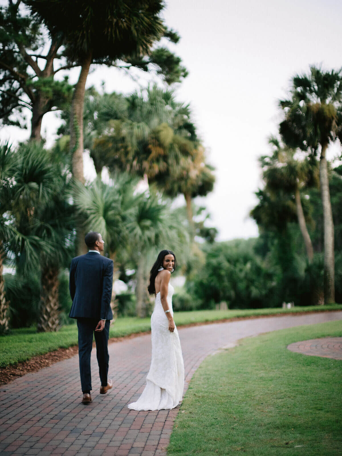 The bride and groom are walking in the well-manicured garden in Montage at Palmetto Bluff. Destination Image by Jenny Fu Studio