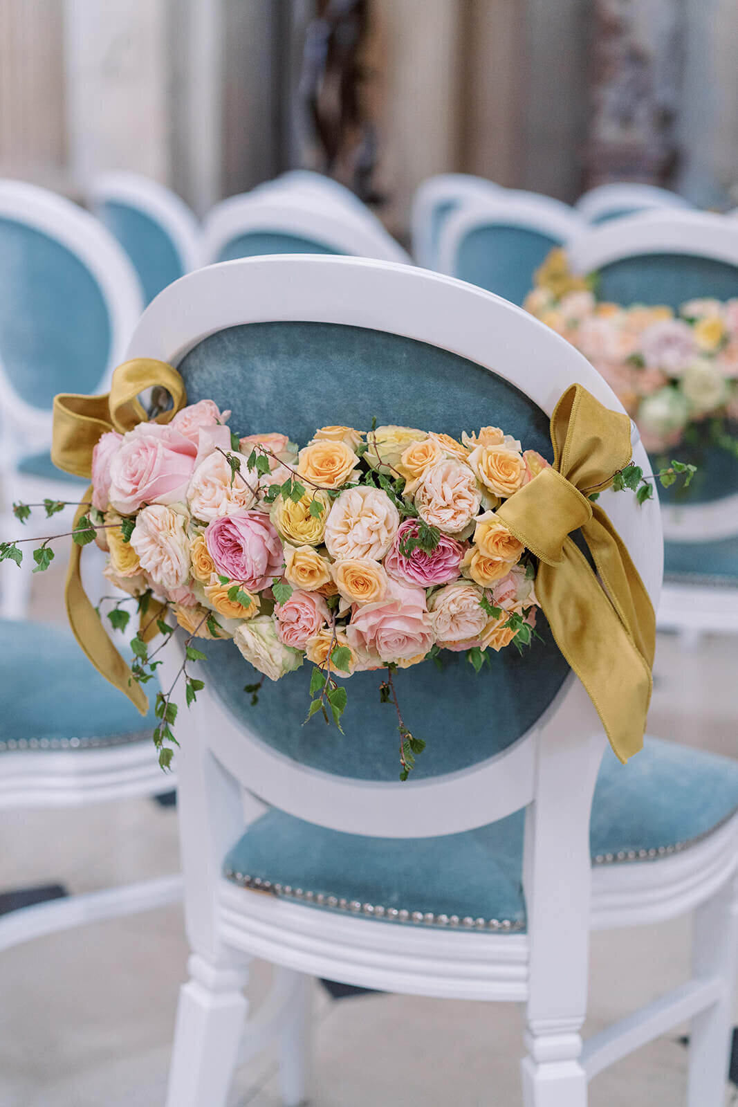 blue chairs at a luxury wedding ceremony at blenheim palace with pink and yellow flower swags on the back of them for a westacott wedding