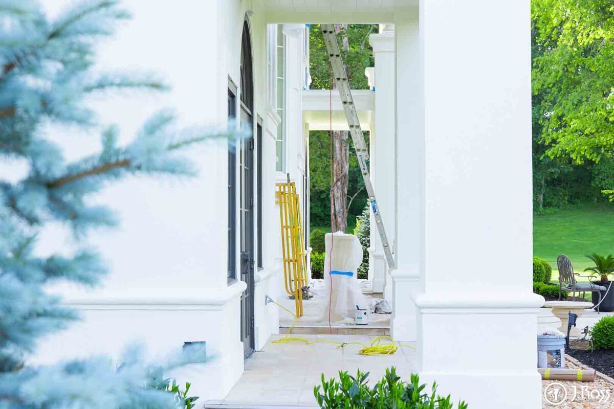 White-painted entryway with columns and trim, showing ladders and drop cloths used for protection, demonstrating meticulous setup for quality home exterior painting Bristol, VA.