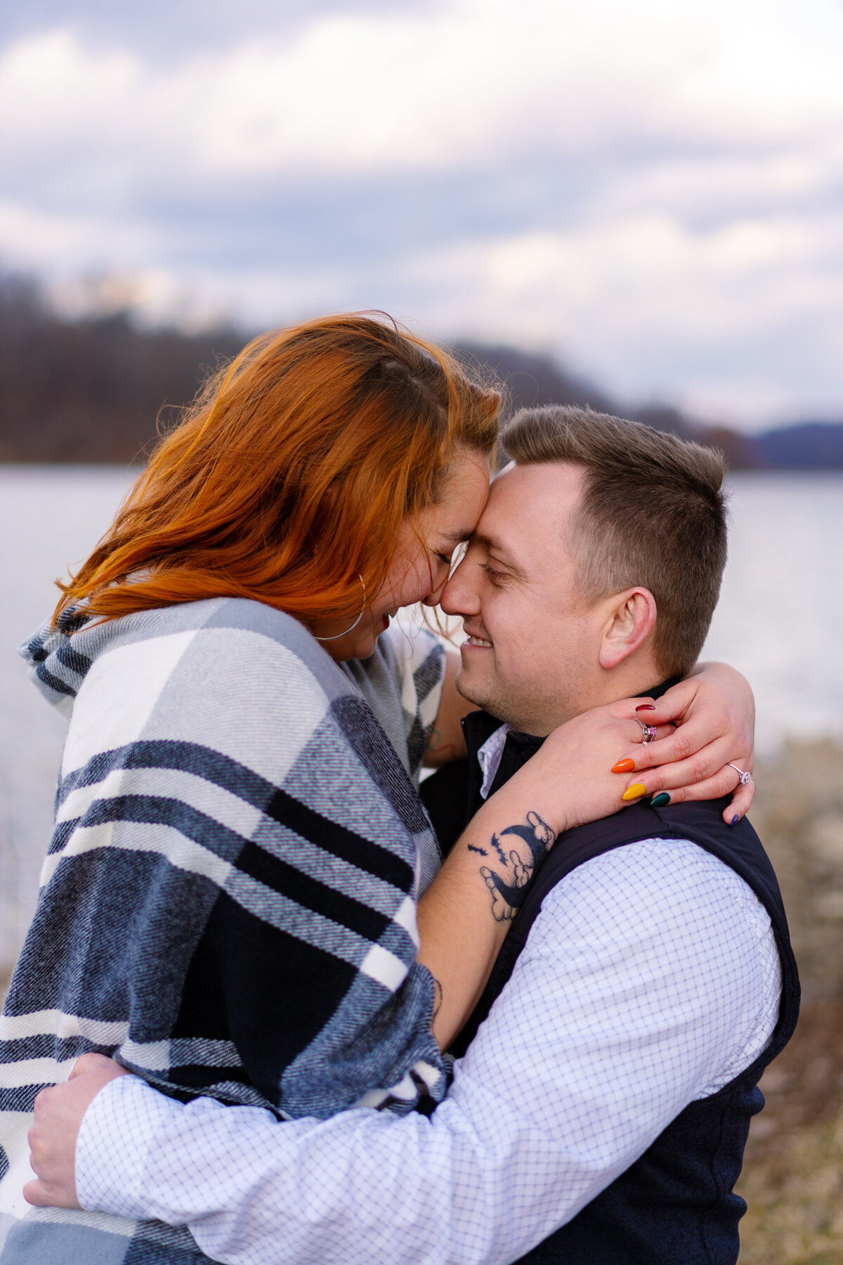 An engaged couple hold each other and touch foreheads while smiling - Salt Fork State Park