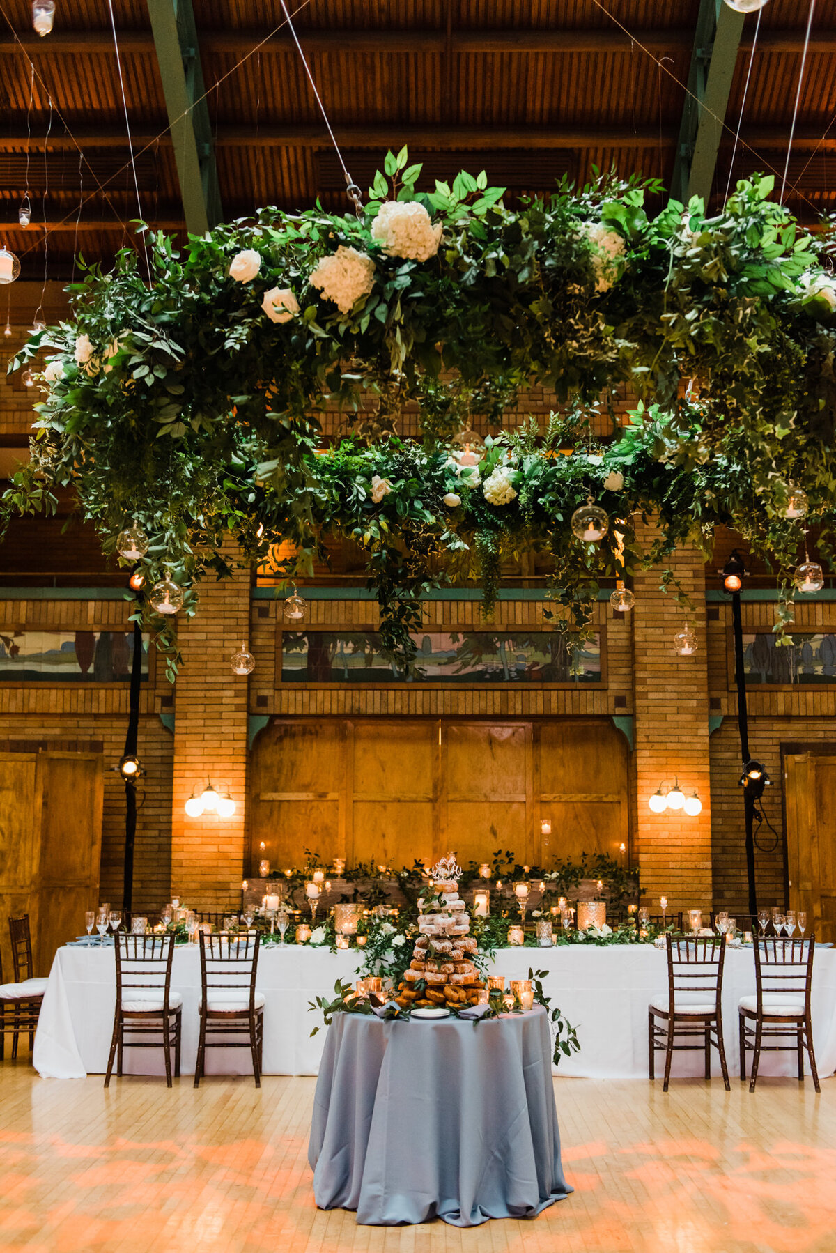 A breathtaking floral ceiling installation at a wedding reception inside Café Brauer, featuring lush greenery and hanging flowers.