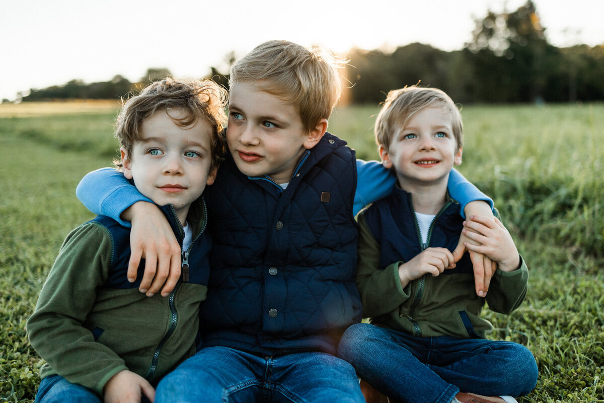 Three brother sitting with arms around each other at sunset