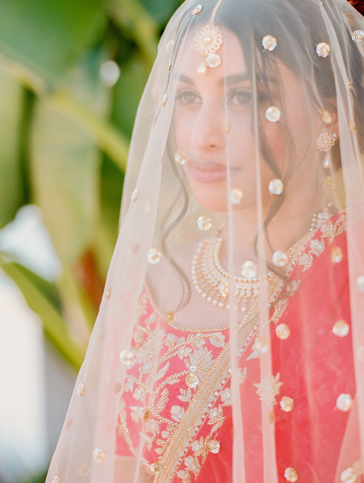 close up of bride under veil with red sarie