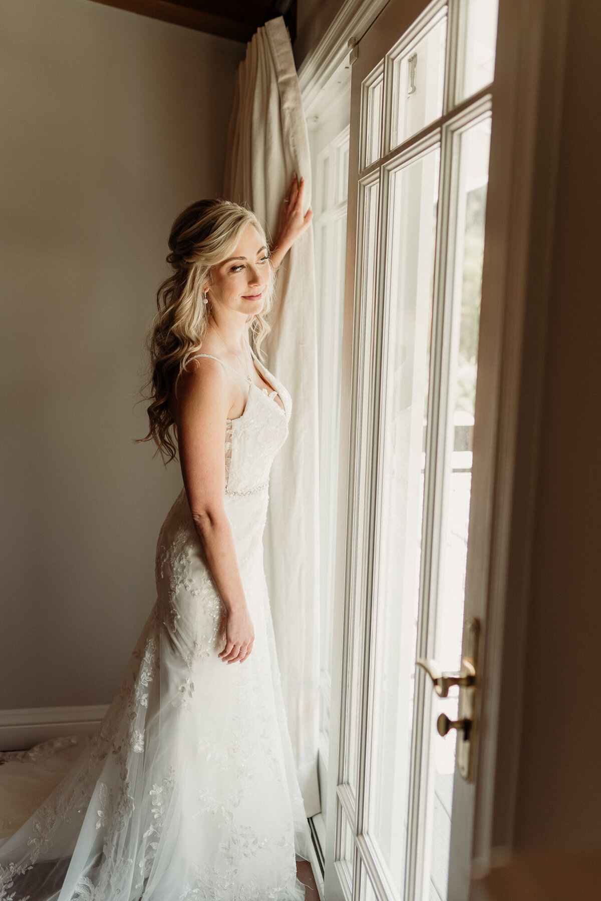 bride standing in a window looking out over her wedding venue - los angeles wedding photographer