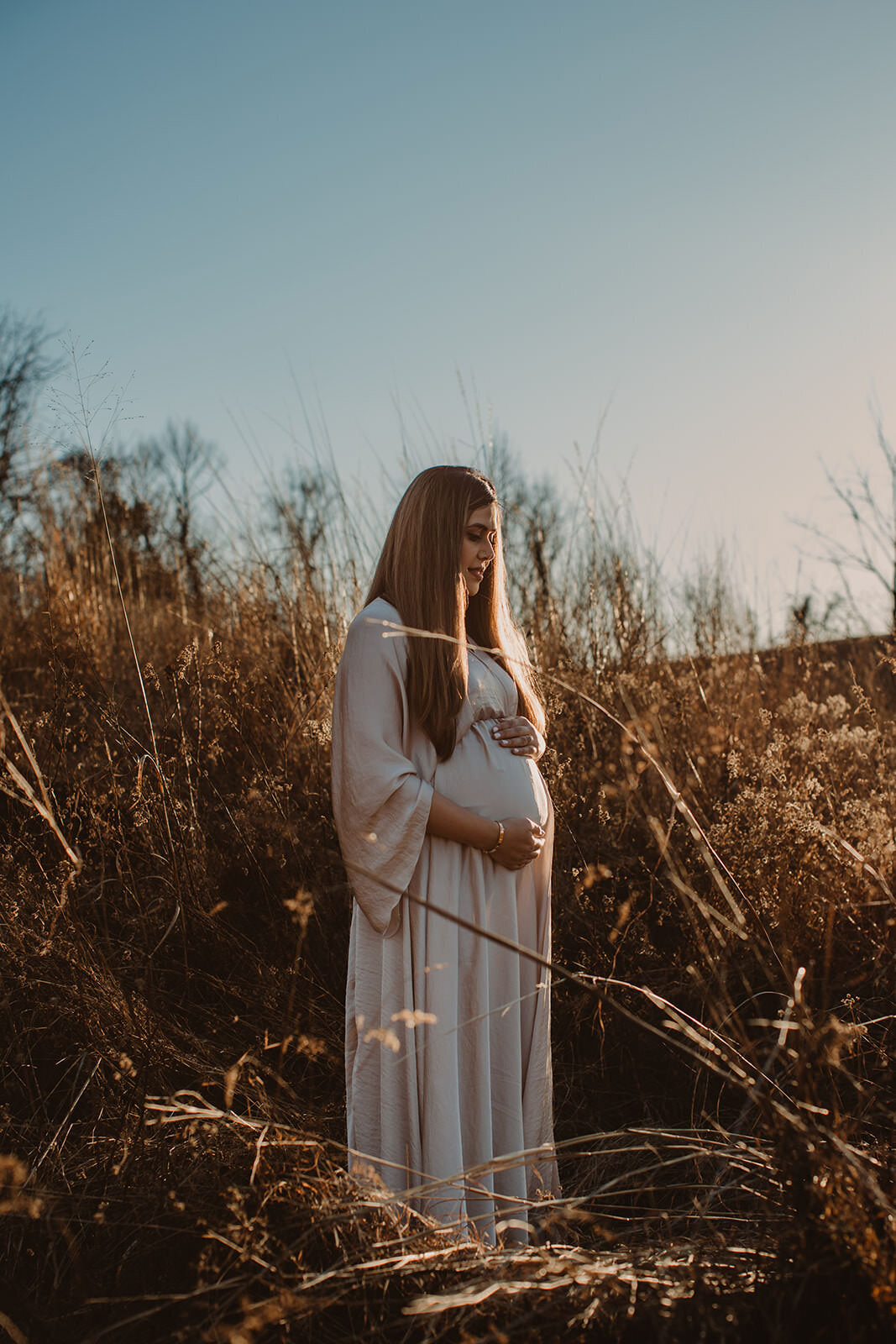 A pregnant person surrounded by tall grass 