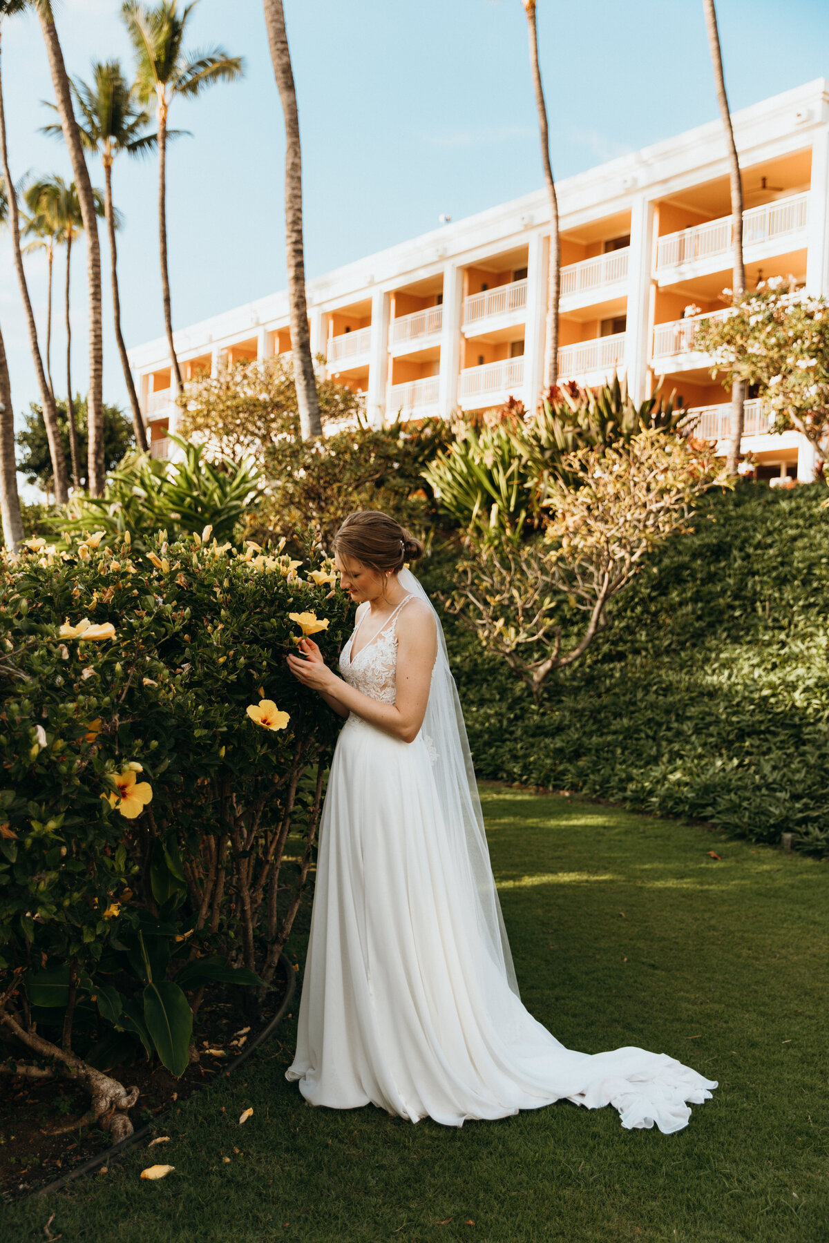 Maui Wedding Photographer captures bride smelling flowers before Maui beach wedding