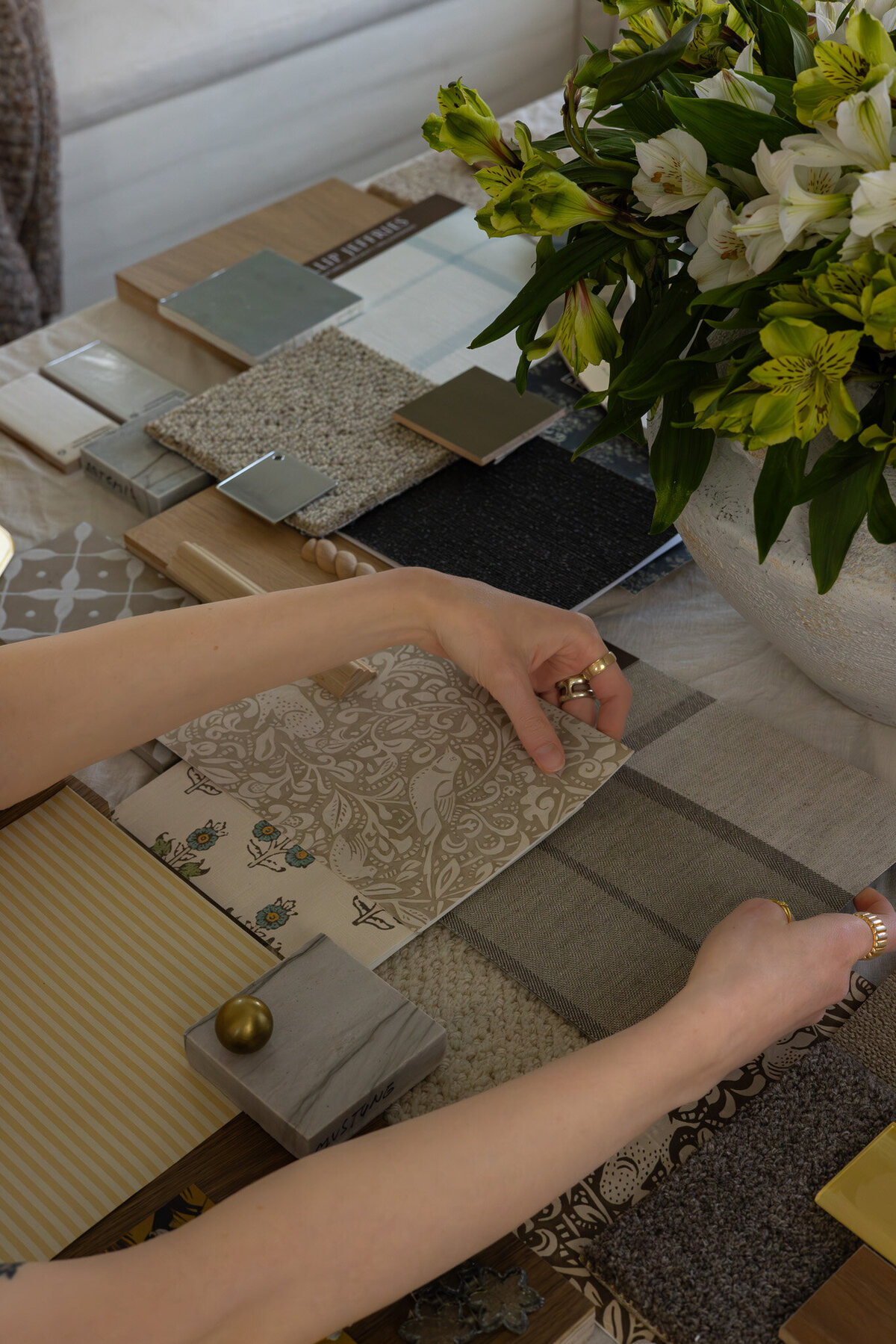 Close-up shot of finishes and material boards with a floral arrangement, by Sister Studio