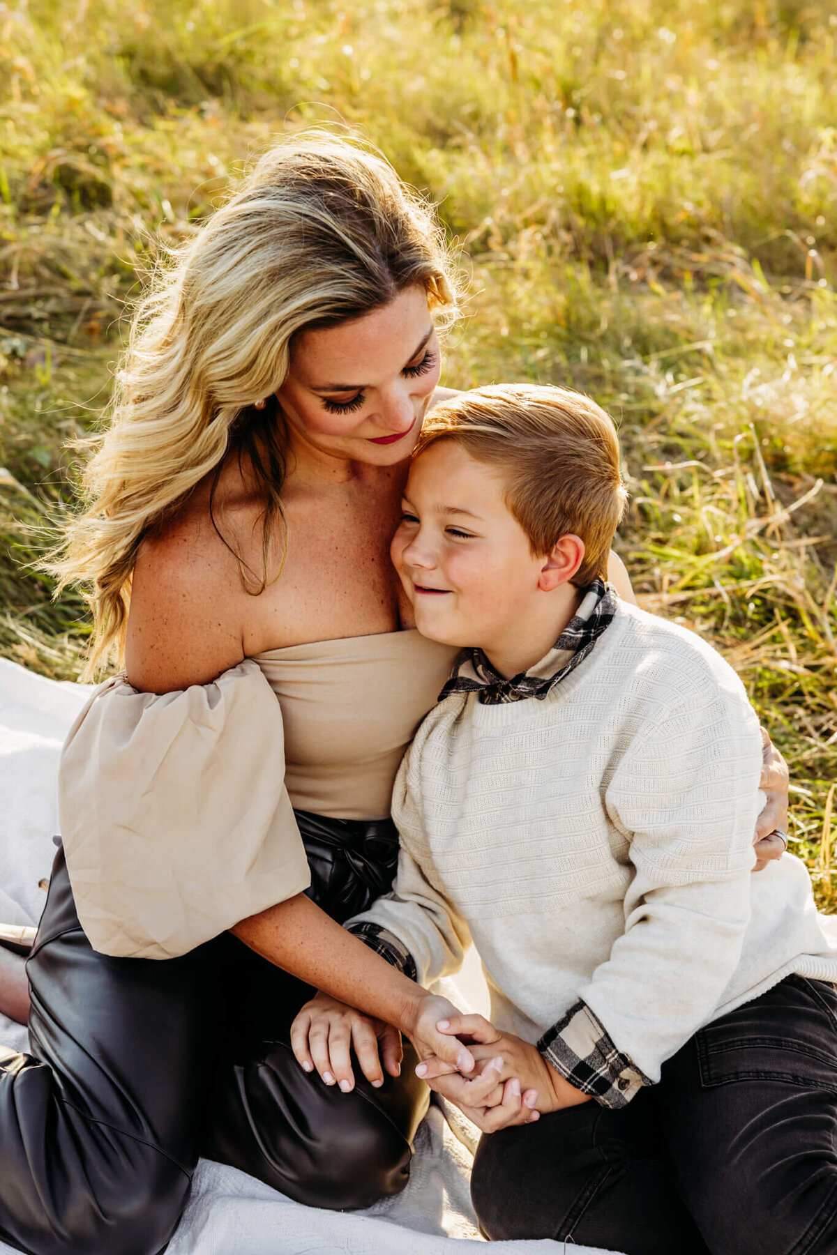 gorgeous mom snuggling her son as they hold hands and have a beautiful moment together captured by Ashley Kalbus Photography