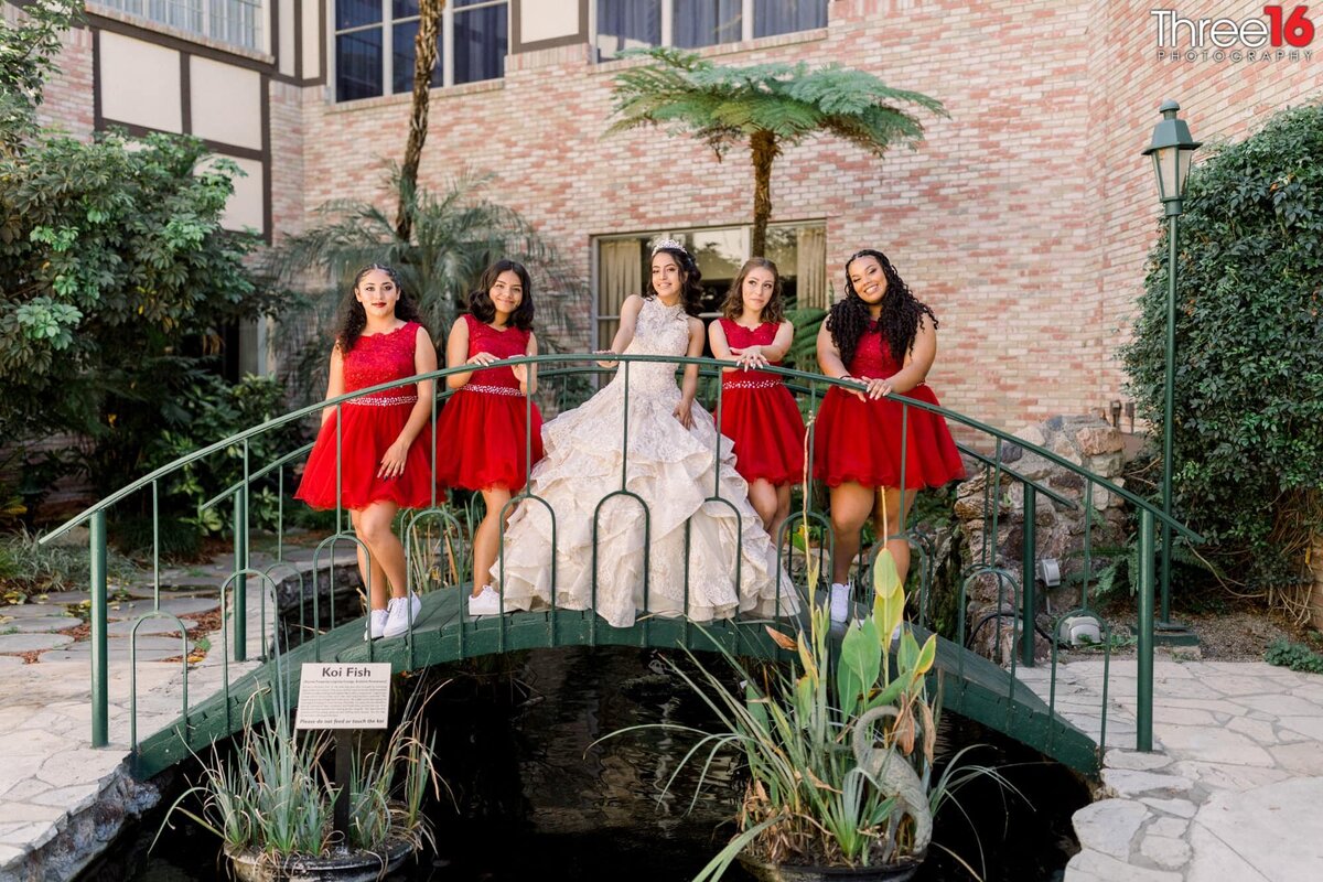 Young girls dressed in red dresses pose with the young lady celebrating her quinceanera