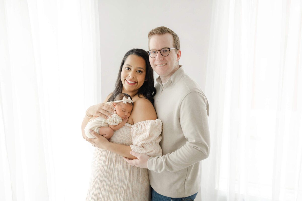 precious oklahoma family in a natural light studio snuggling their newborn daughter