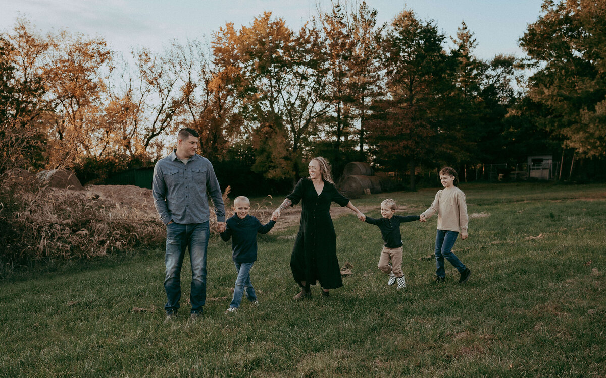 A family of five holds hands as they walk across the field on their farm in Denver Colorado