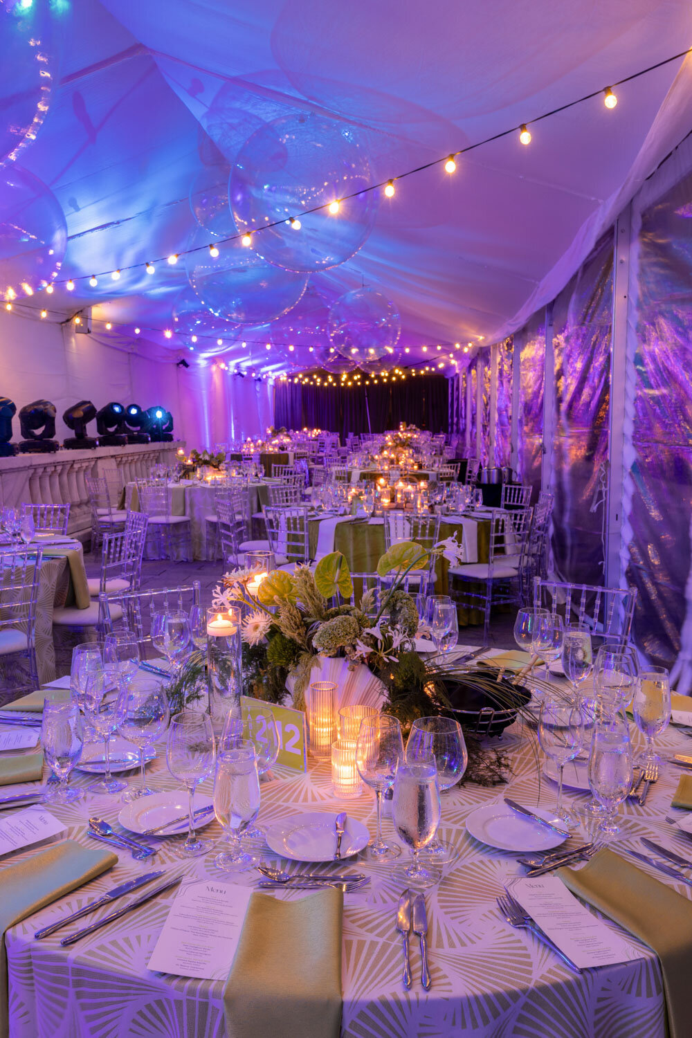 Tent reception with glowing lights and beautifully set tables