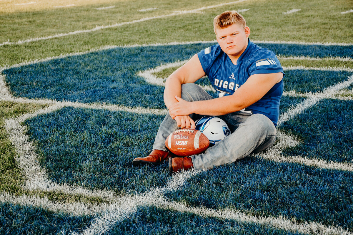 Senior boy on a football field with a football in Idaho