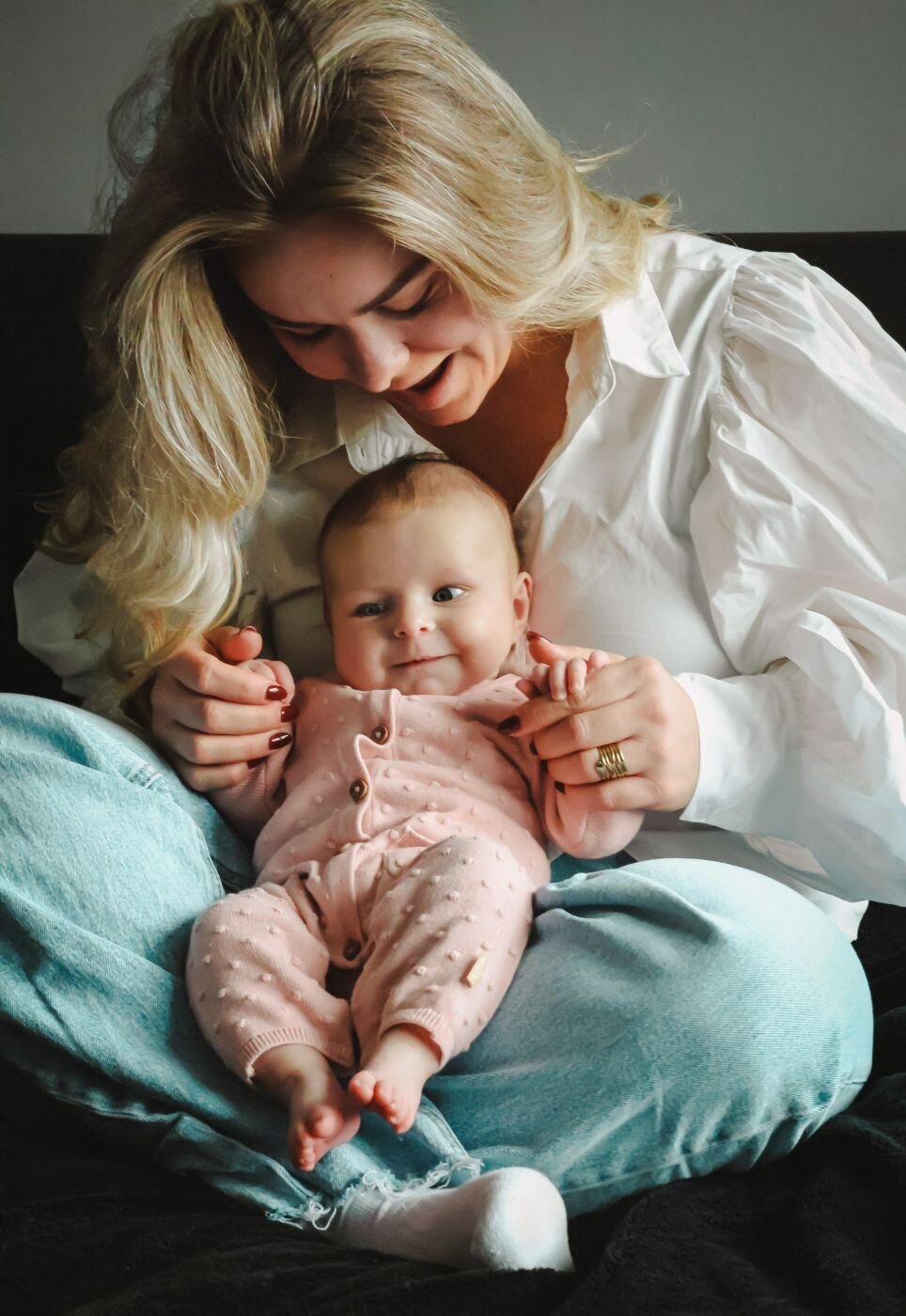 Een liefdevolle foto van een moeder die haar baby vasthoudt en naar haar kijkt, met een zachte glimlach op haar gezicht