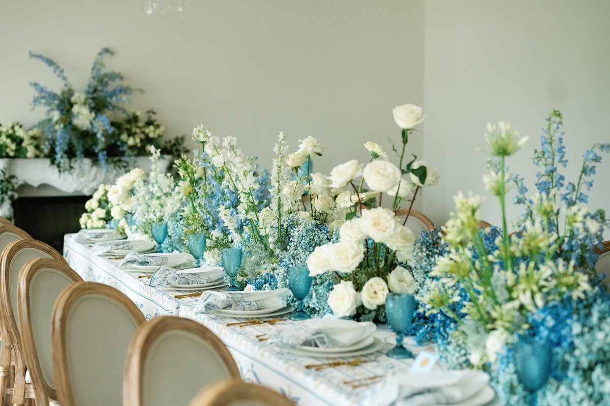 This breathtaking wedding tablescape is adorned with a plush blue floral runner that cascades gracefully to the floor, creating a statement piece of luxury and romance. The combination of lush textures and cascading florals brings depth and movement to the design, making it the perfect inspiration for couples seeking a refined, elegant reception aesthetic.