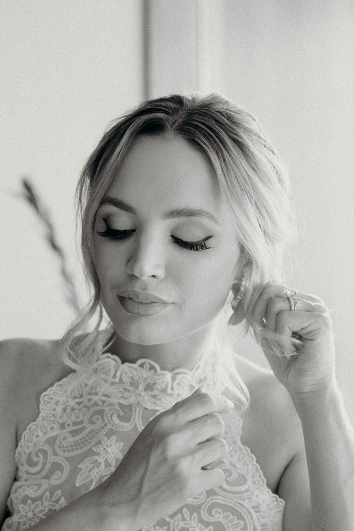 bride puts on her earrings and preps her bridal hair updo for the big moment before walking down the aisle