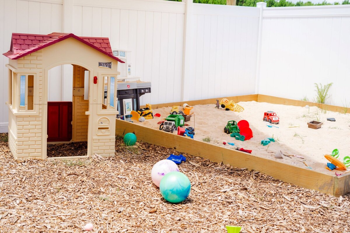 The outside play area including a playhouse and sandpit at the Nest, a preschool and learning center in Surf City, NC