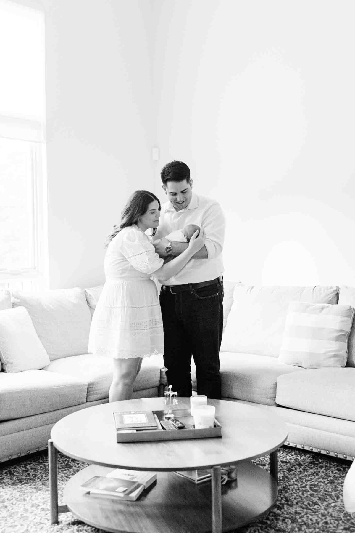 New parents snuggling on living room couch with newborn child