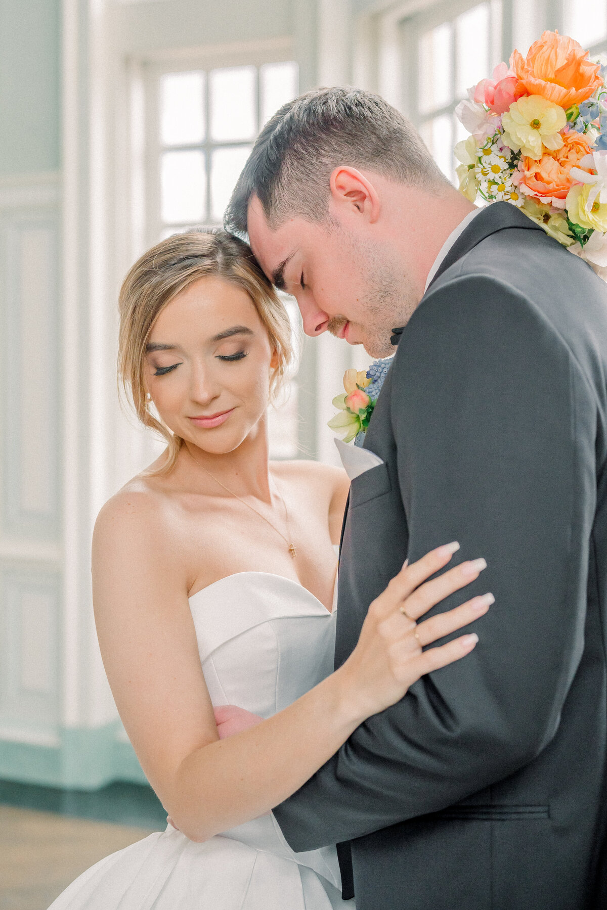 Groom nuzzling bride during portraits in a beautiful white and blue ballroom