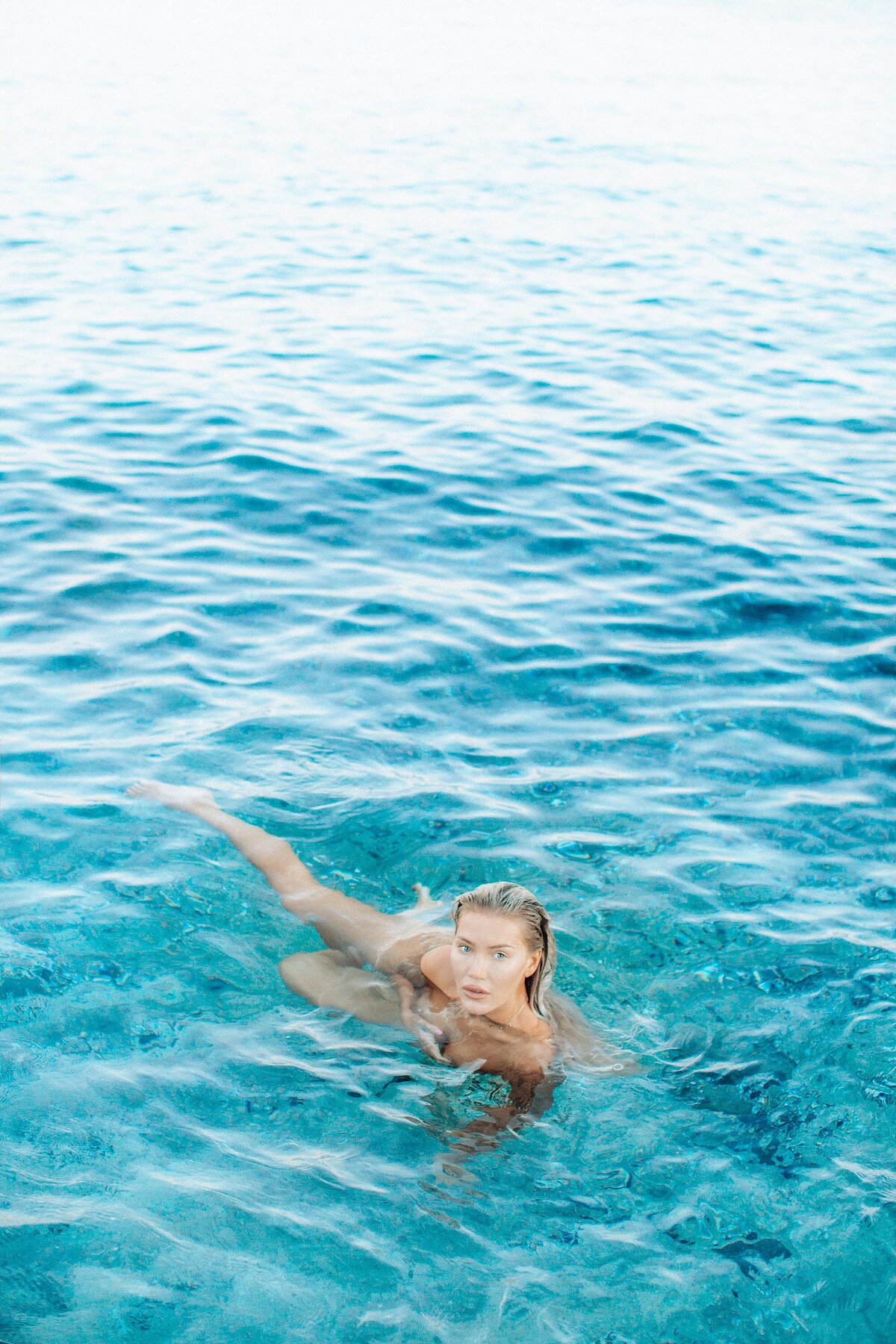 Boudoir photo of a blonde woman swimming in the beautiful blue waters of Maui