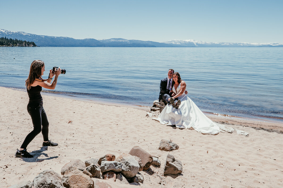 Lake Tahoe elopement photographer capturing a couple on the beach with crystal-blue water, soft sand, and snow-capped mountains in the background.