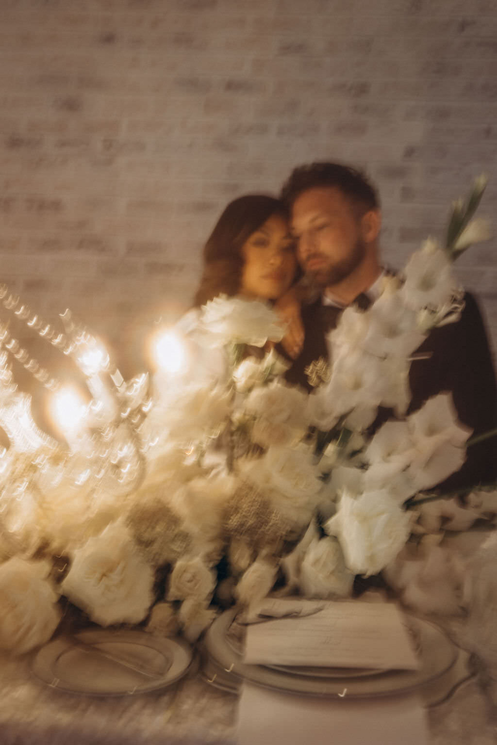 A large bouquet of flowers with a newlywed couple sitting behind it.