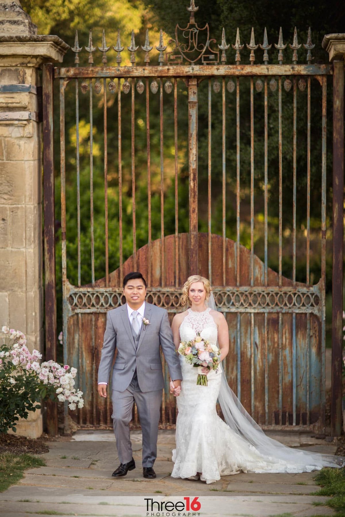 Newly married couple pose in front of the main gate