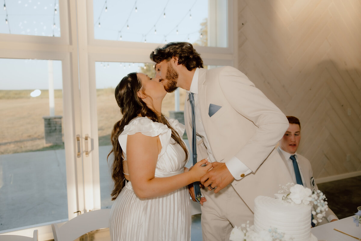 bride and groom kissing after cutting the wedding cake