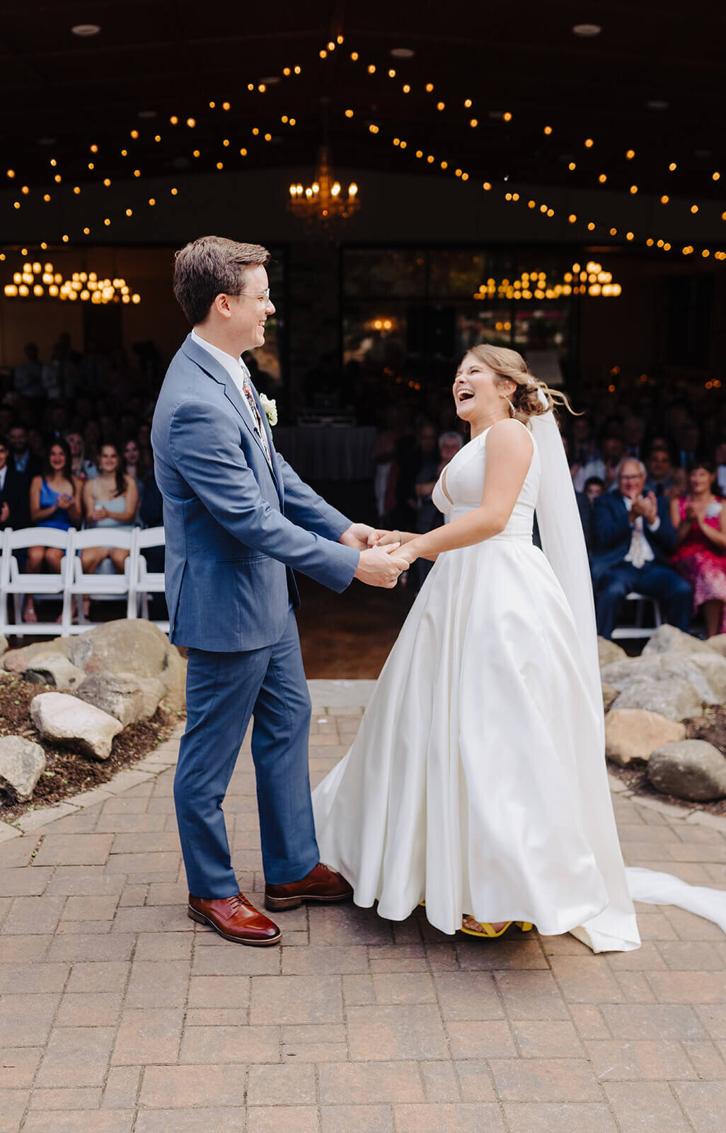 Bride and groom standing together laughing in front of wedding guests at Oswego wedding, NY