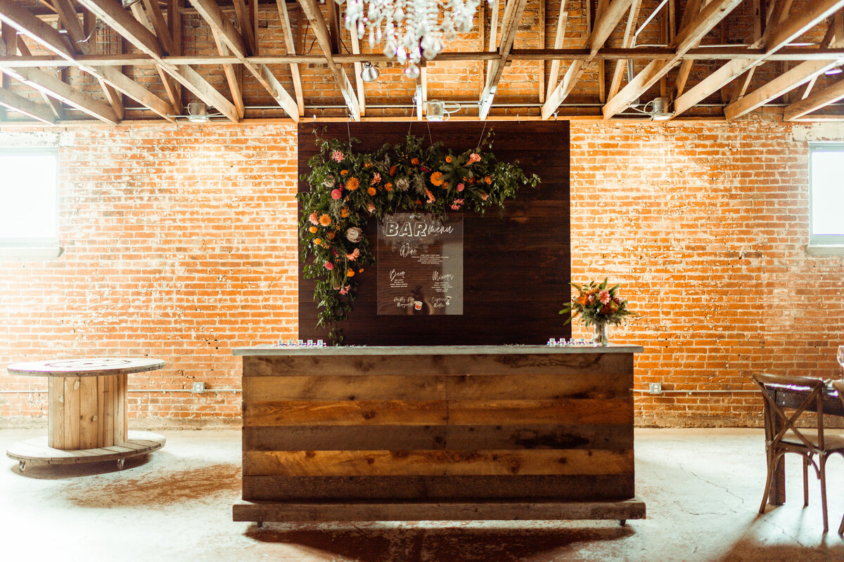 Walnut backdrop with bright florals behind the bar at the St Vrain, Colorado wedding venue