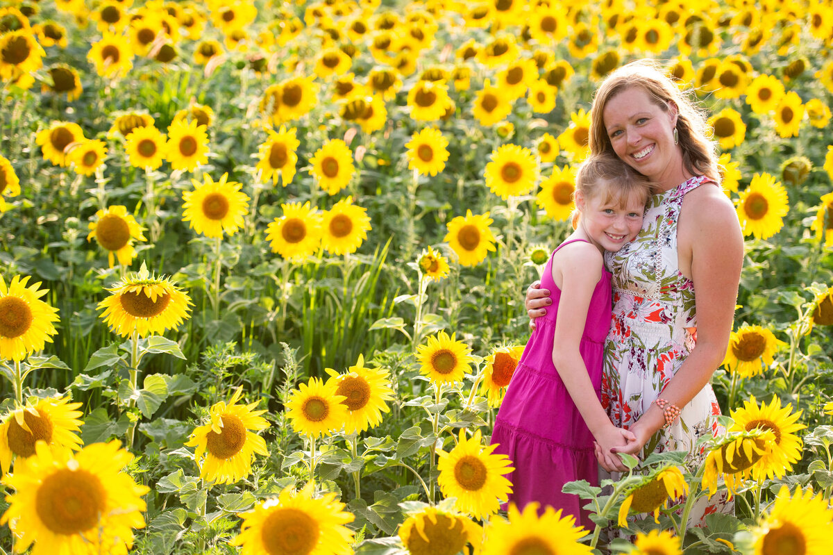 Ottawa Family Photography of a mom and daughter hugging in a filed of sunflowers at sunset
