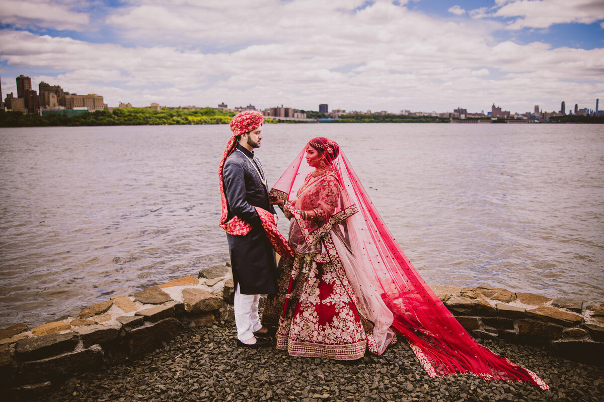 pakistani and bengali muslim with veil dupatta over the bride in front of water at fort lee park