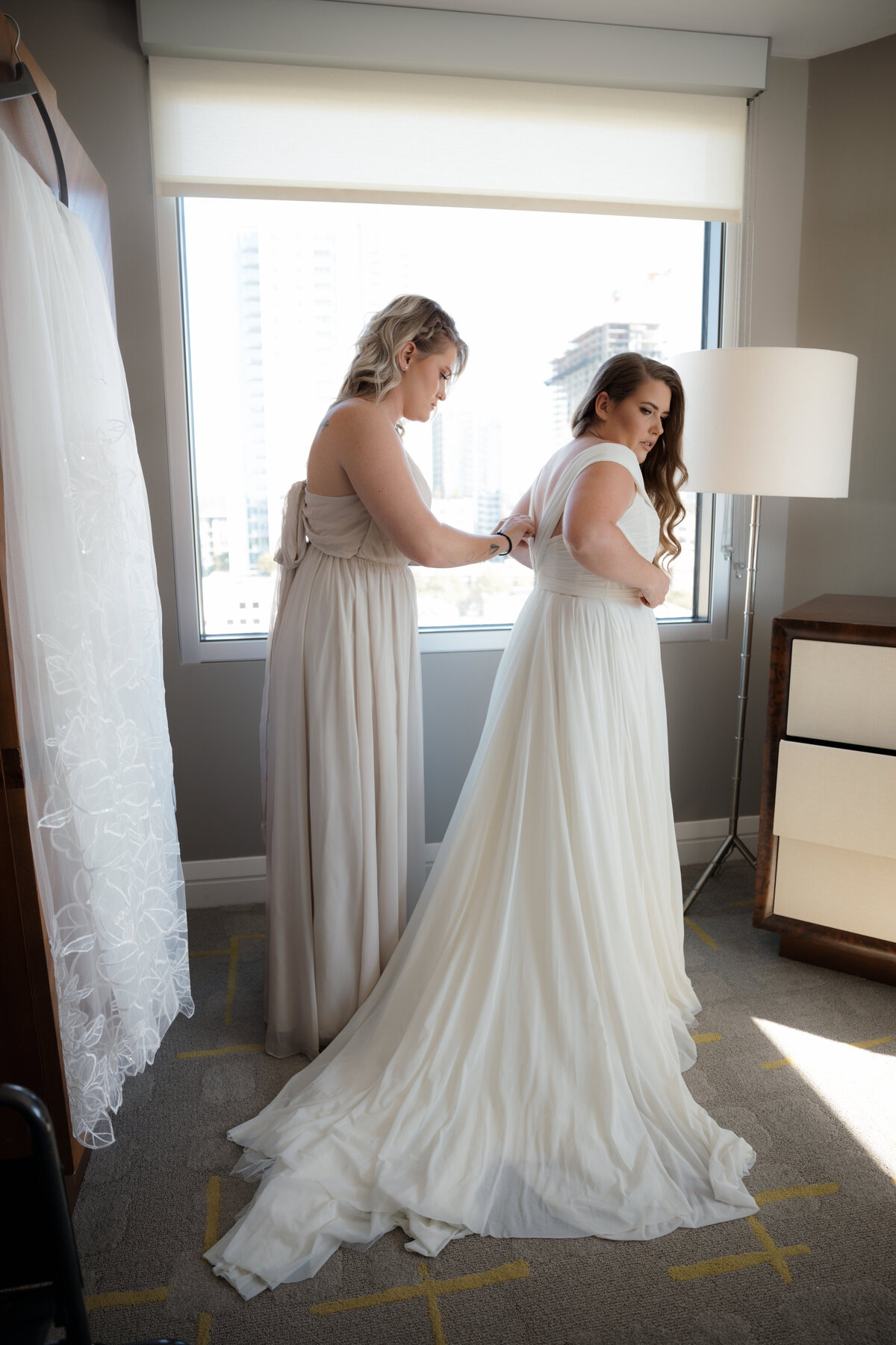 Bride preparing for her wedding day, gently adjusting her veil and dress in a peaceful, light-filled room.