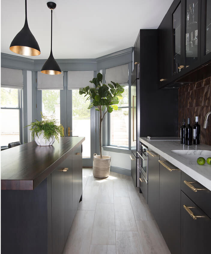 Best Interior Designers in Boston create a modern kitchen with dark grey cabinets, wood counters, brass hardware, and Aerin lighting from Visual Comforts.