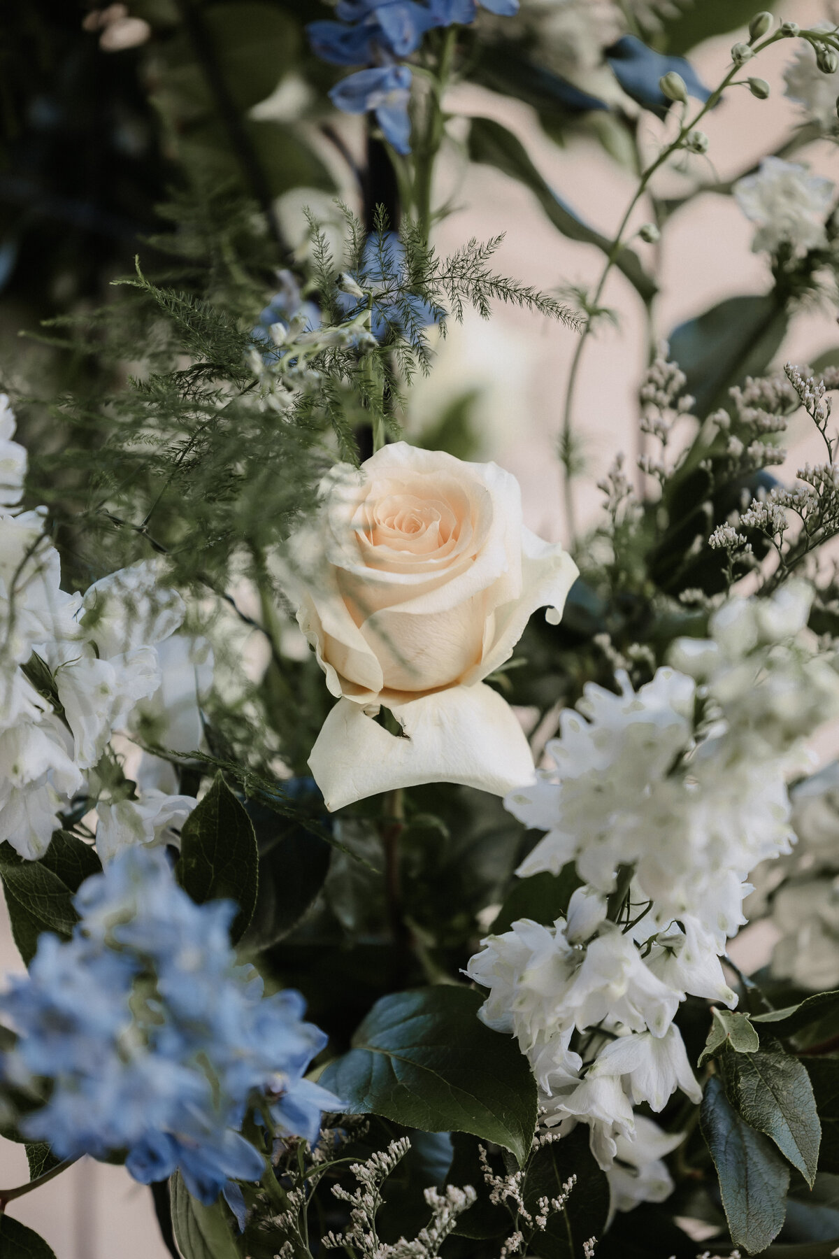 Close up detail shot of wedding flowers with a yellow rose, white and blue flowers and greenery