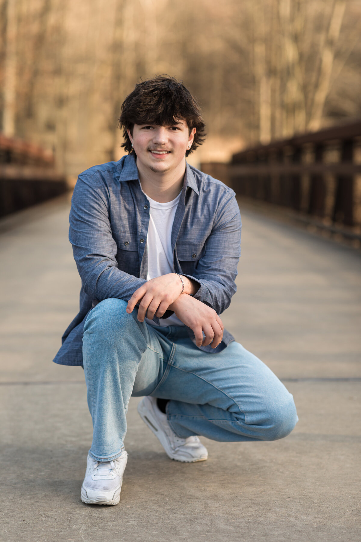 male high school senior in blue button down posed at Westcreek reservation for senior portraits