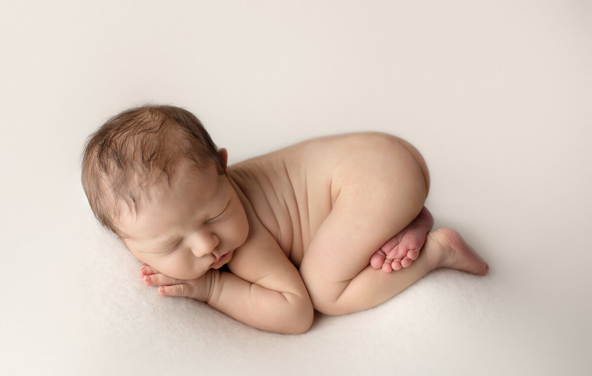 simple newborn posing on cream backdrop in denver newborn  photography studio