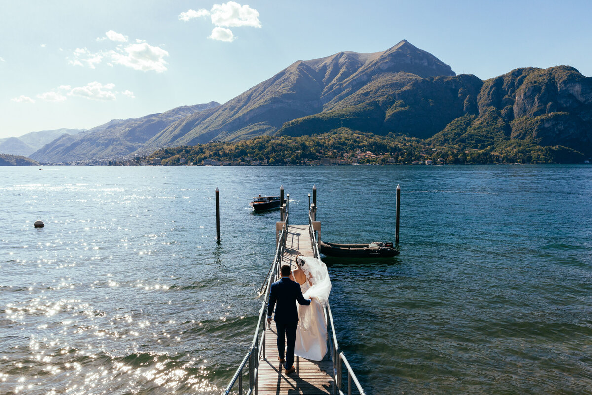 A couple walking down a small dock towards a boat.