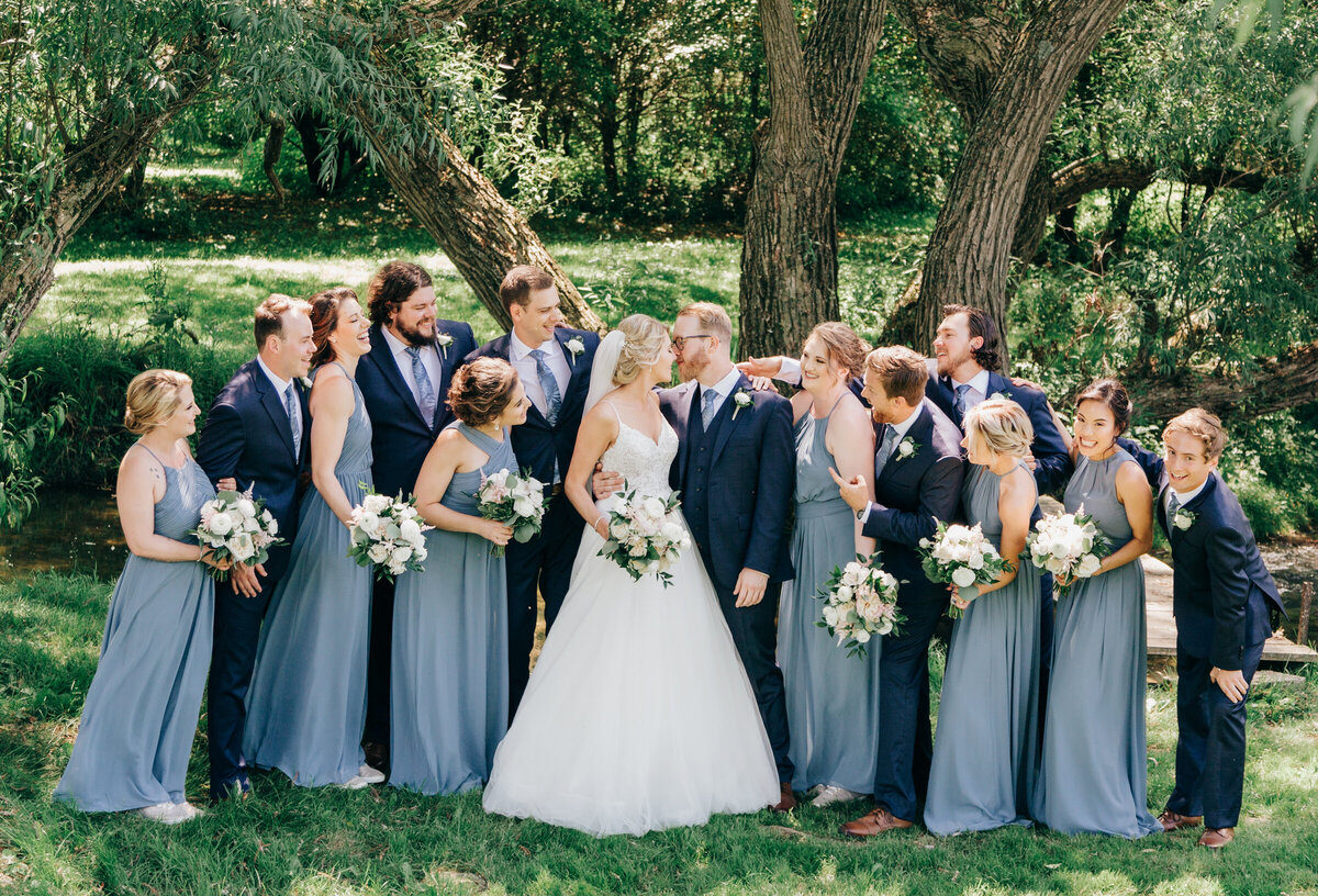 Outdoor wedding party portraits of groomsmen in navy suits and bridesmaids in blue dresses