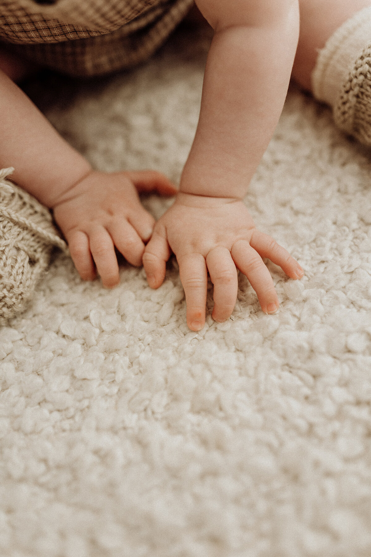 a little babies chubby fingers against a textured mat