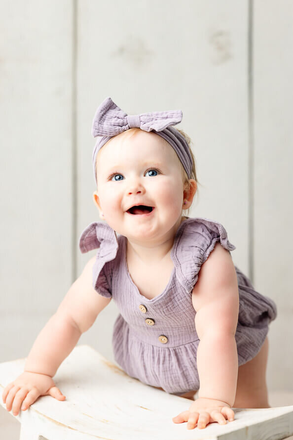 Baby girl smiles at Angela Marie Media.