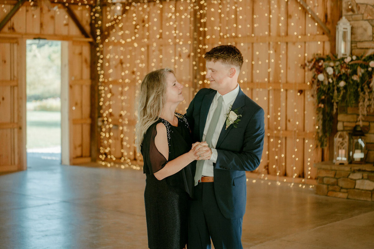 Mother and groom share a dance in a warmly lit hall