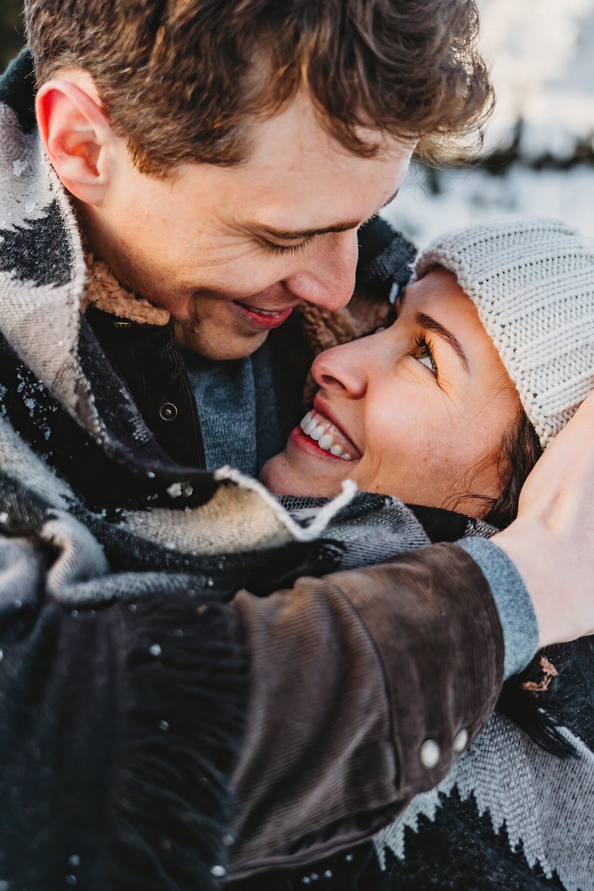 close up shot of a couple on Mt Rainier snuggled in a blanket in the snow