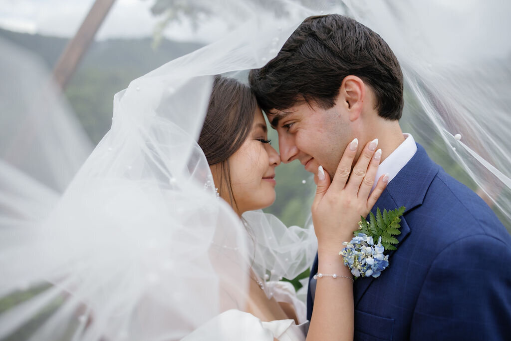 Gatlinburg elopement captured by wedding photographers gatlinburg tn with bride and groom embracing under the brides veil and smiling as the bride holds the grooms jaw 
