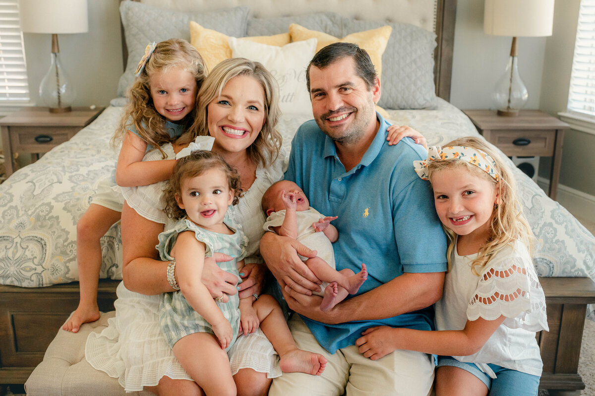 Family of 6 with new baby smiling at camera by Cypress Texas Photographer