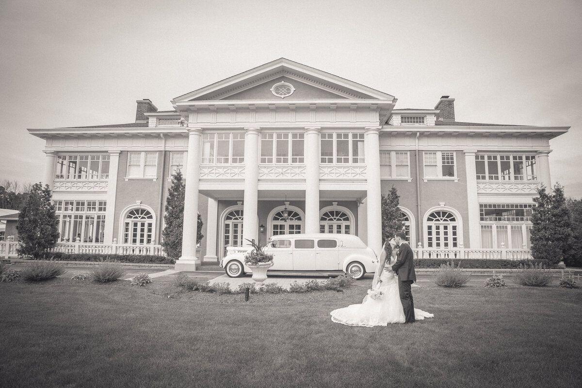 A romantic wedding photo in front of a vintage car and a mansion in Illinois.