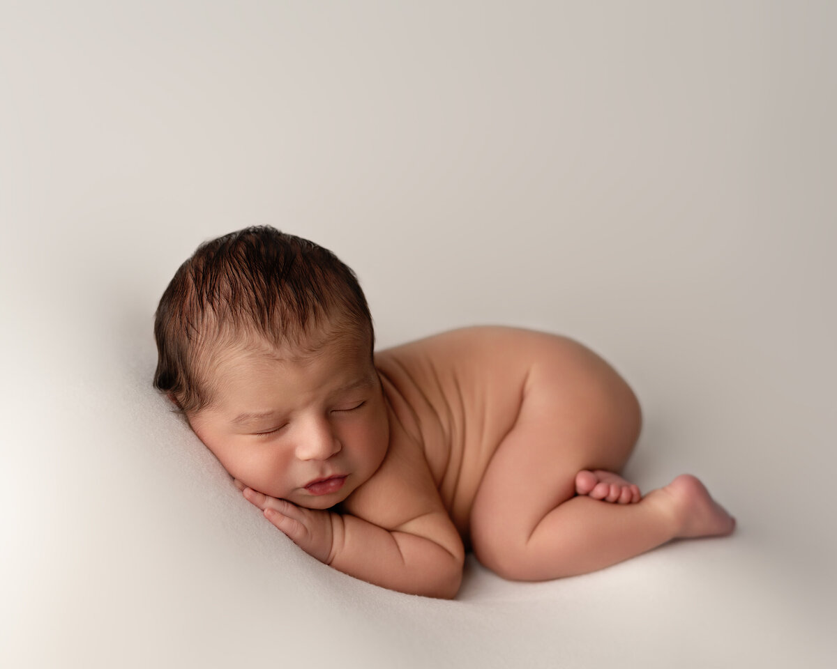 A peaceful newborn portrait captured in studio with soft beige tones and gentle light. Represents the natural, timeless style of Meraki Photographic Creations in Paris, Ontario.