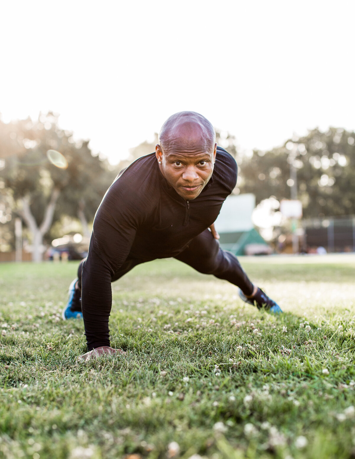 Man facing camera doing one arm plank in grass