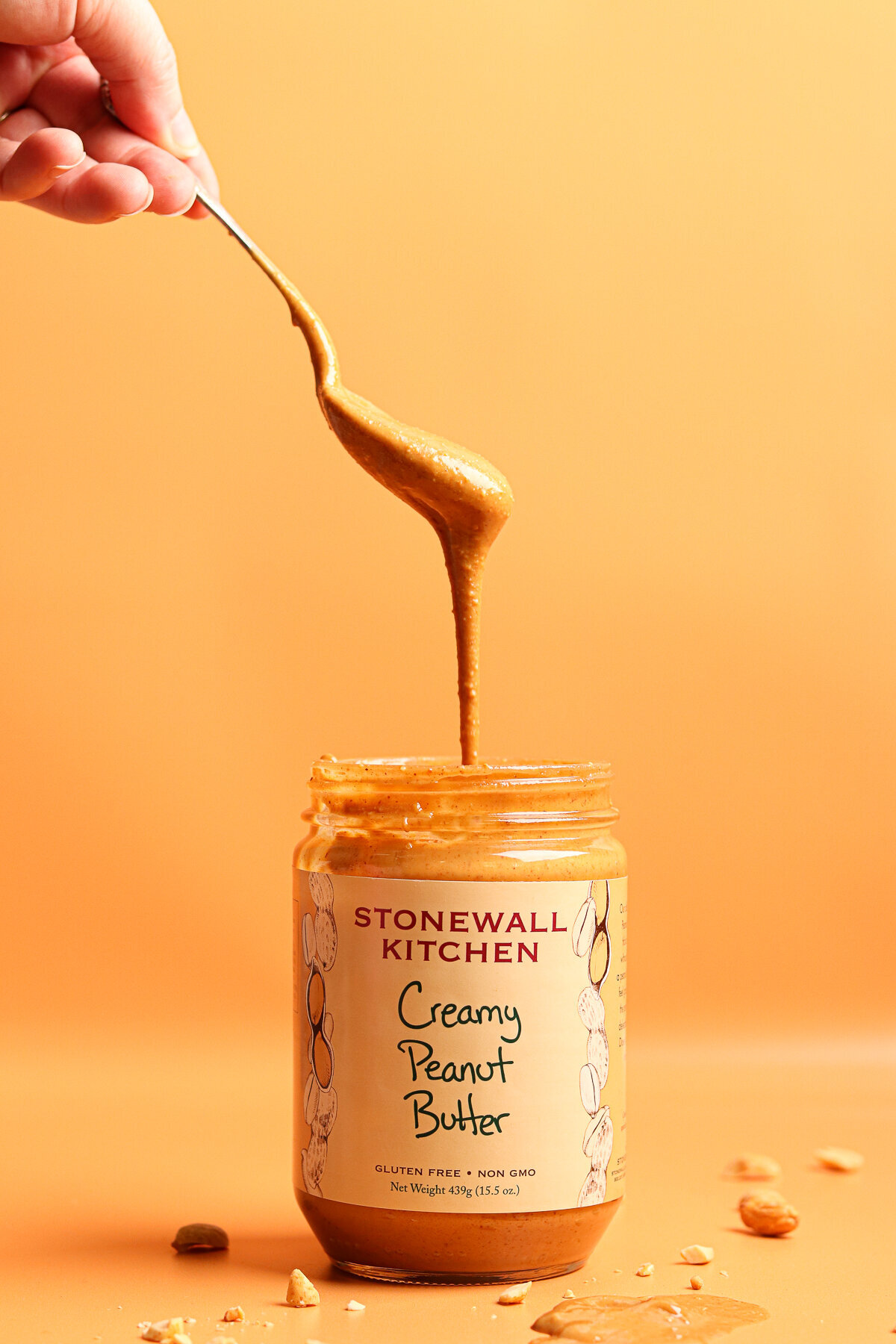a spoon drizzling peanut butter down into a jar of Stonewall Kitchen peanut butter